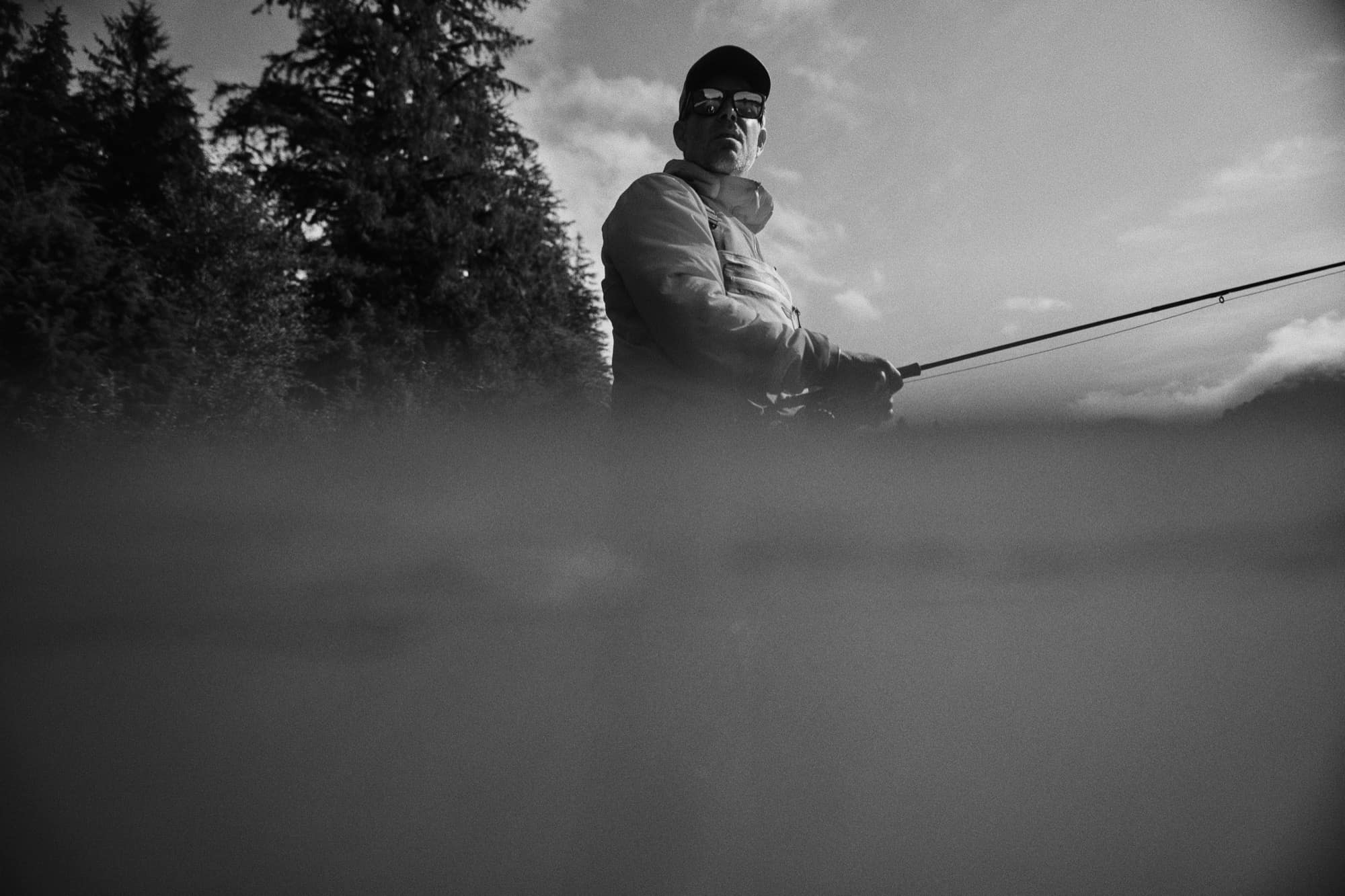 Angler casting in misty water