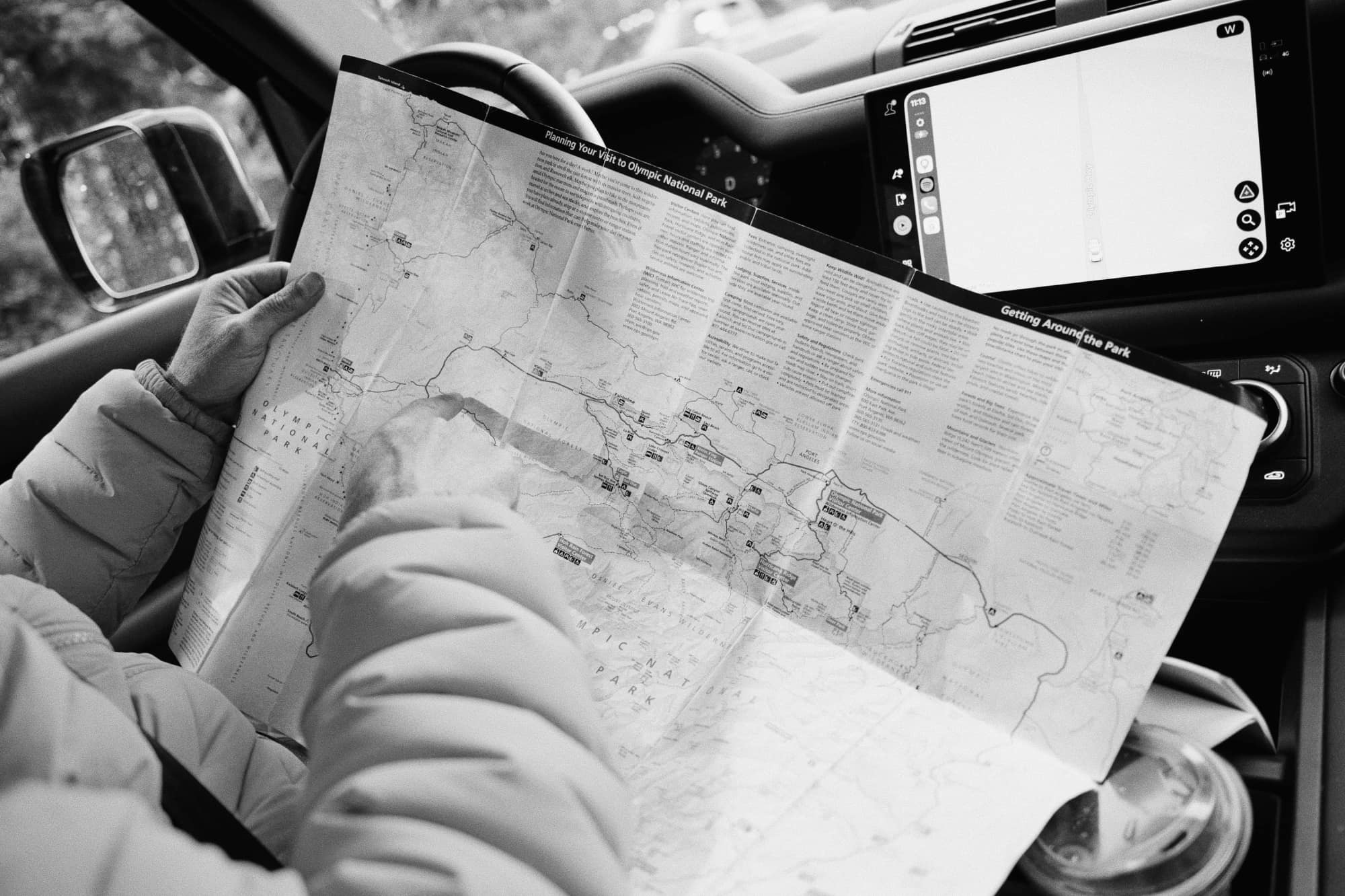 Hands holding a map while planning a trip from inside a vehicle